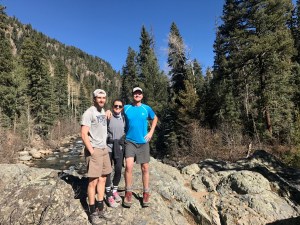 Zoe and two coworkers on top of a rock 