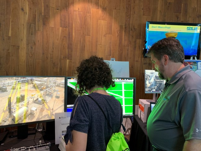 Williams employee and student standing in front of monitors reviewing technology we use to build pipelines. 