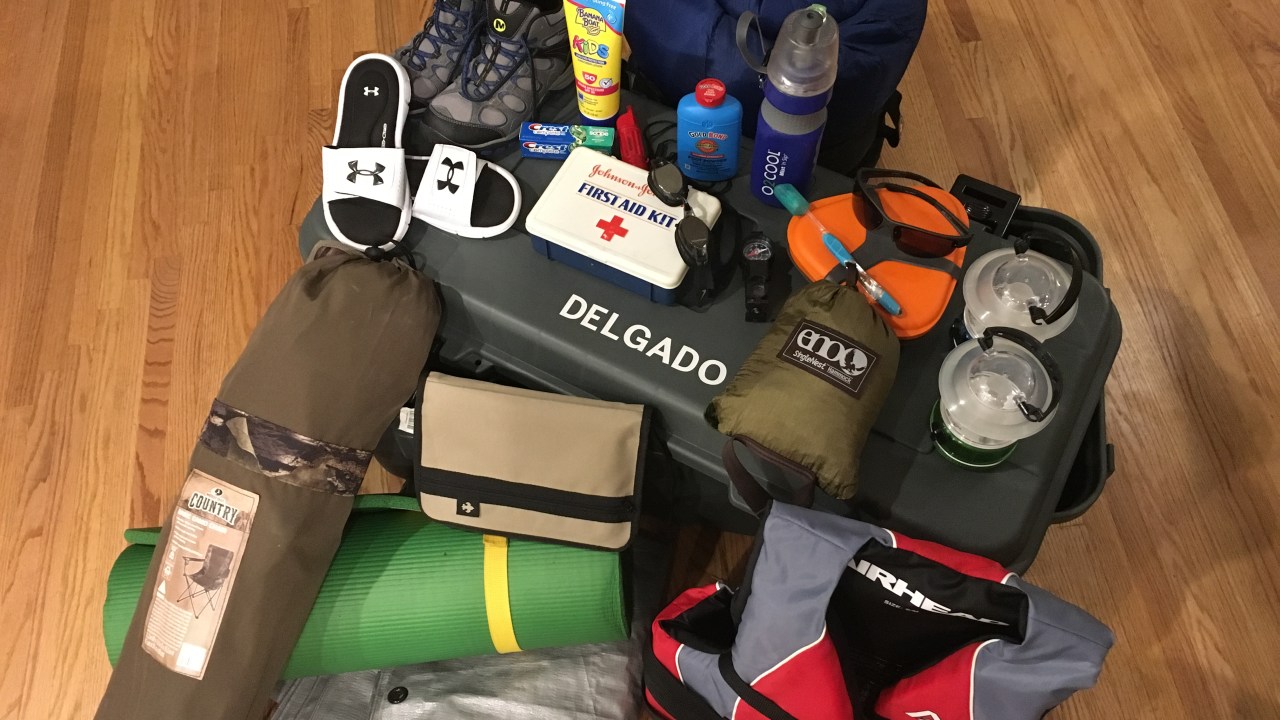 Hiking boots, sunscreen bottle, toothpaste, whistle, first aid kit, goggles, compass, mess kit, toothbrush, hammock, lanterns, sleeping bag, foot powder bottle, flip flops, nylon book cover, camp chair, sleeping pad, tarp, life preserver, foot locker.