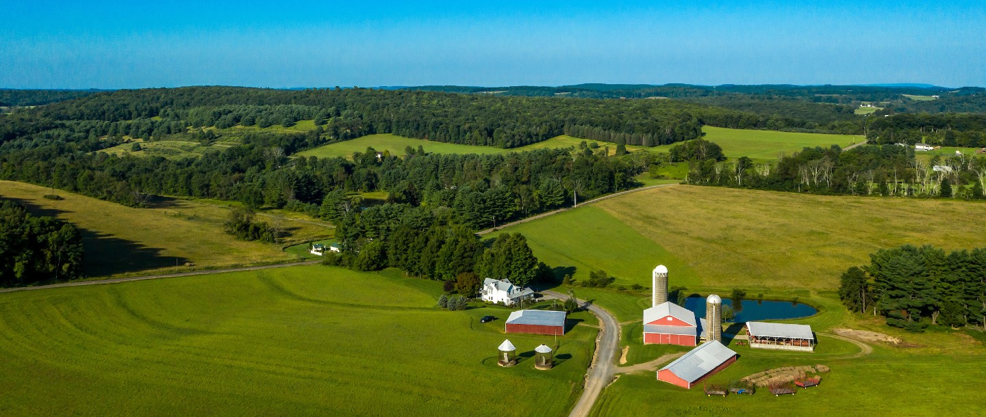 Photo of farm with silo surrounded by green rolling landscape